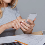 Mujer haciendo registro de sus gastos mensuales a través del celular